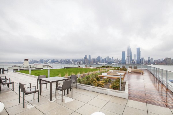 Scenic rooftop terrace with seating, greenery, and city skyline views at Harbor 1500 Apartments