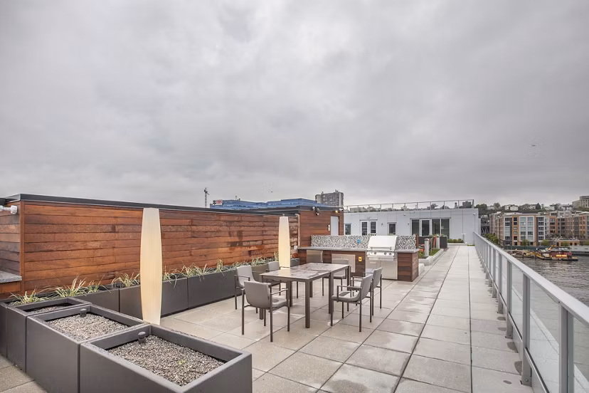 Rooftop patio with seating, lush planters, and city skyline at Harbor 1500 luxury apartments