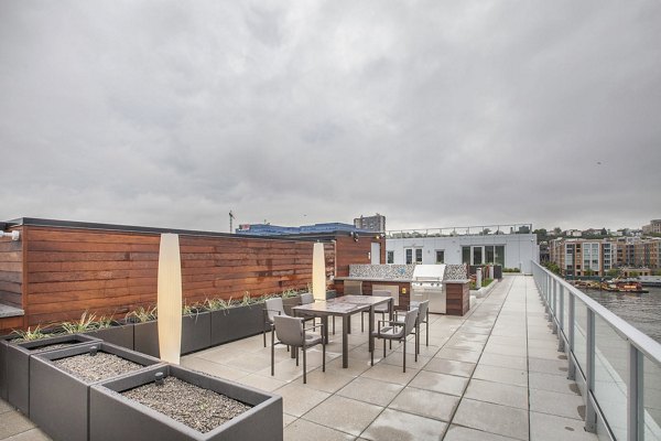 Rooftop patio with seating, lush planters, and city skyline at Harbor 1500 luxury apartments