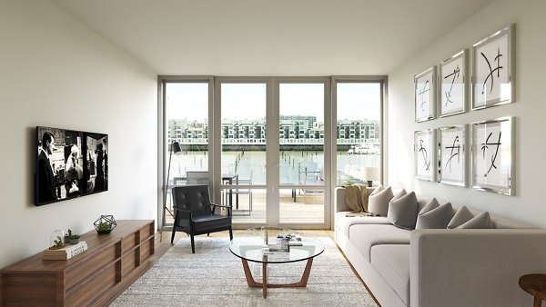 Bright living room with large windows and waterfront view in Harbor 1500 Apartments, featuring minimalist decor