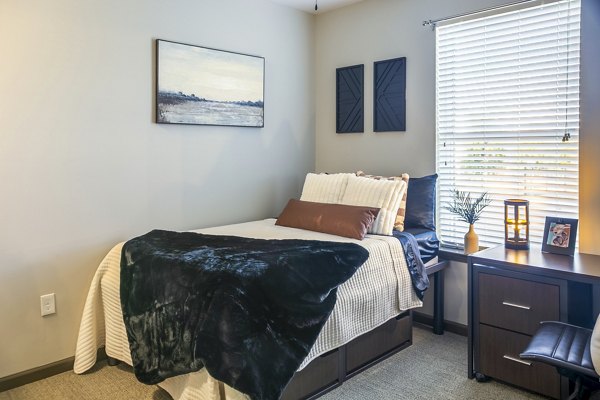 Cozy bedroom with modern decor at College View Apartments, featuring a plush bed and large window for natural light Ideal for restful living