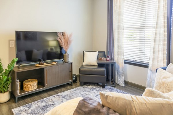 Spacious modern living room with stylish furniture and large windows at College View Apartments, offering comfortable luxury apartment living