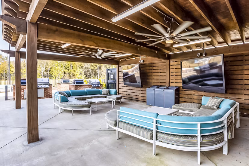 Outdoor grilling and patio area at College View Apartments featuring modern seating and lush landscaping