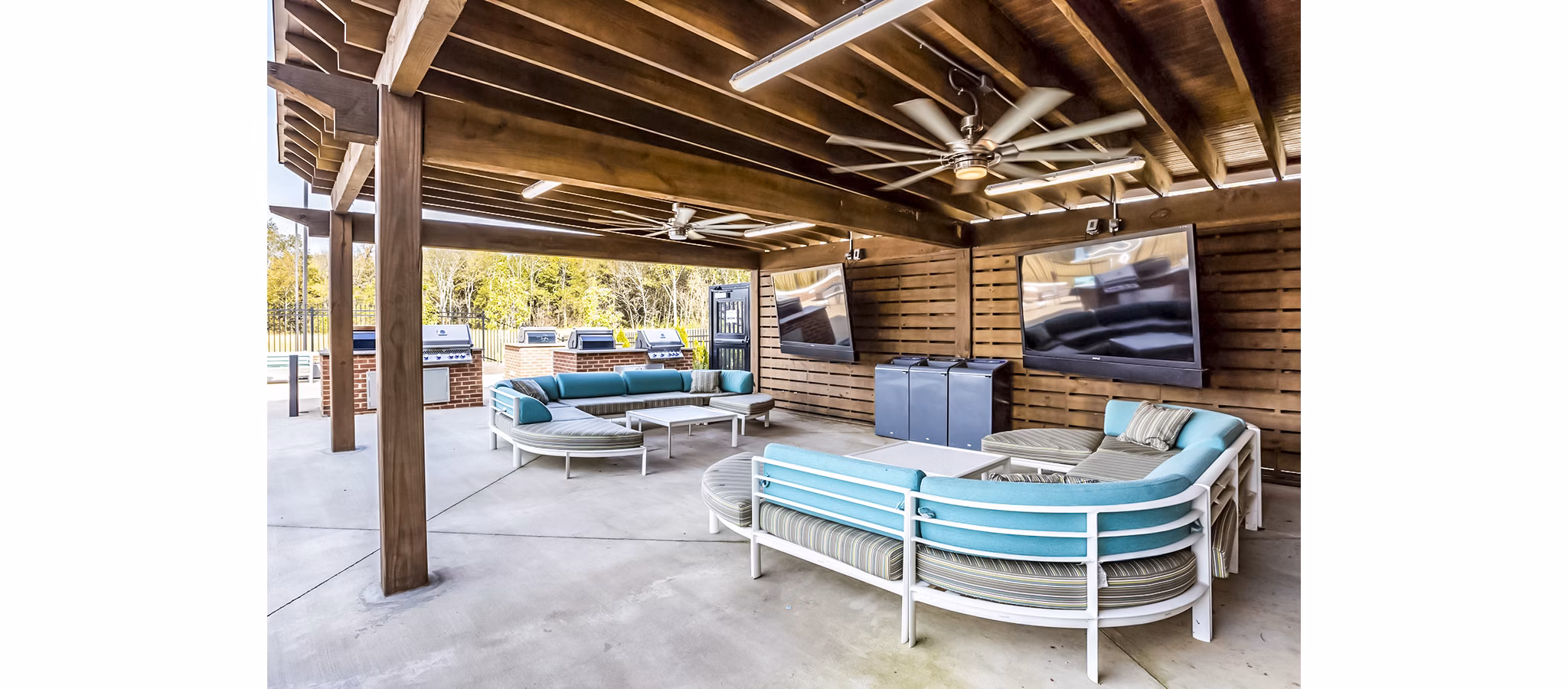 Outdoor grilling and patio area at College View Apartments featuring modern seating and lush landscaping