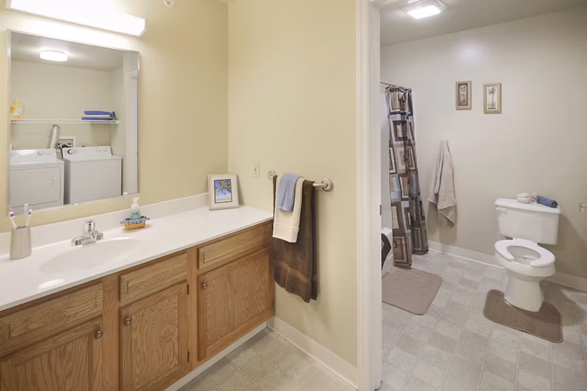 Elegant bathroom with marble countertop and glass shower in Evergreen Commons Apartments