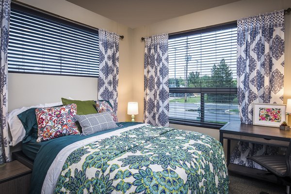 Bedroom with modern decor and large windows at SkyVue Apartments in a luxury setting Perfect blend of comfort and style for urban living