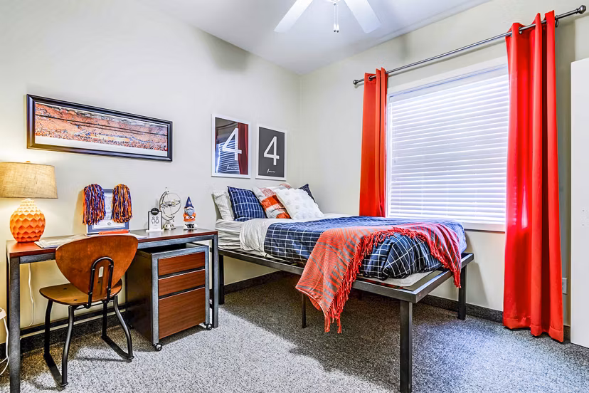 Bedroom with modern furnishings at University Village Apartments On Colvin, a luxury property managed by Greystar