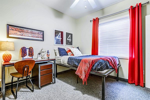 Bedroom with modern furnishings at University Village Apartments On Colvin, a luxury property managed by Greystar