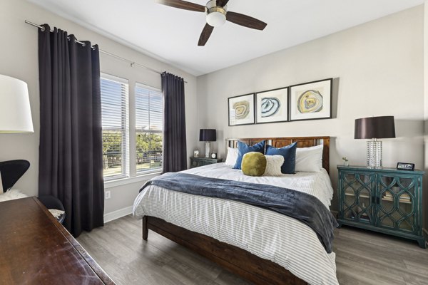 Cozy bedroom with elegant decor and large window at The Michael at Presidio Apartments, offering luxury living experience