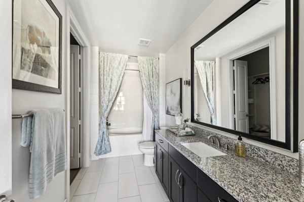 Luxurious bathroom with marble countertops and glass shower at The Michael at Presidio Apartments