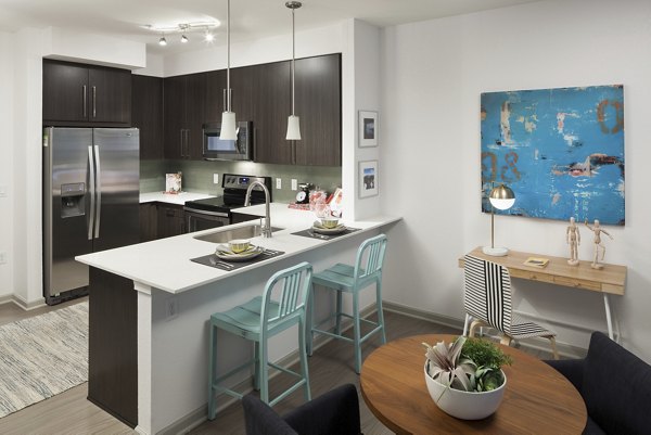Modern kitchen with stainless steel appliances and granite countertops at Alexan West Highland luxury apartments