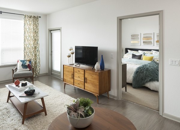 Modern living room with stylish furnishings and large windows at Alexan West Highland luxury apartments