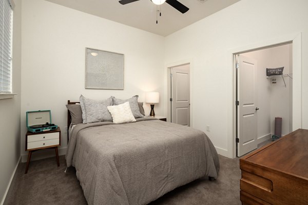 Cozy bedroom with modern decor at The Oliver Apartments, featuring plush bedding and natural light for an inviting atmosphere