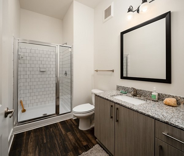 Modern bathroom featuring marble countertops and spacious design at The Oliver Apartments