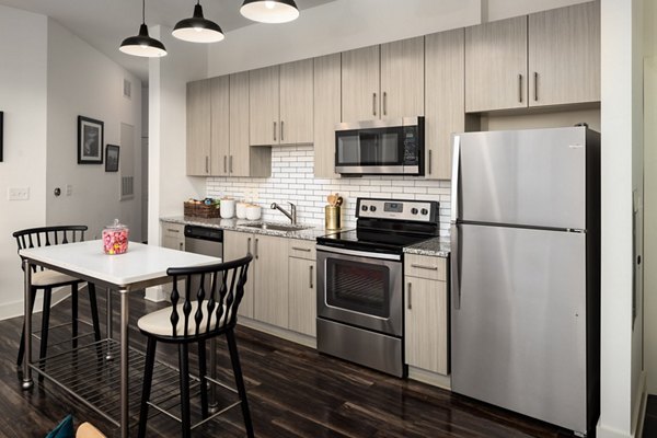 Modern kitchen with stainless steel appliances and marble countertops in The Oliver Apartments