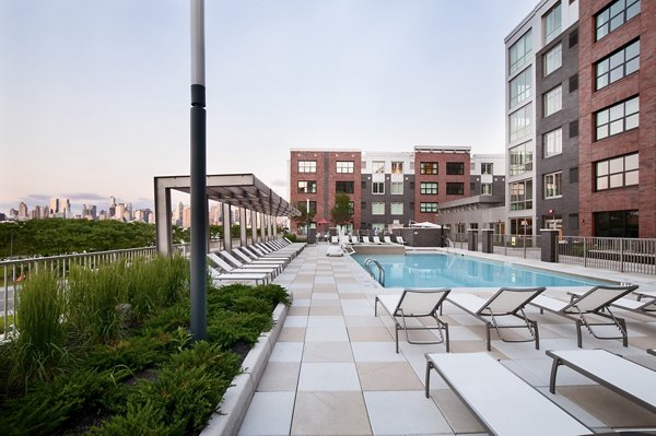 Community pool with lounge chairs surrounded by lush greenery at Estuary Phase II Apartments, a luxury Greystar community