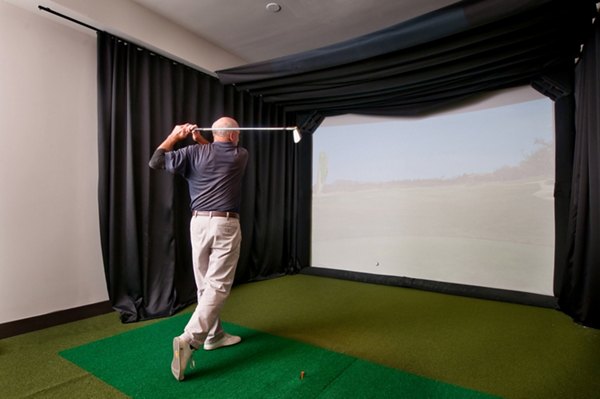 Indoor golf simulator with a player practicing their swing at luxury apartments