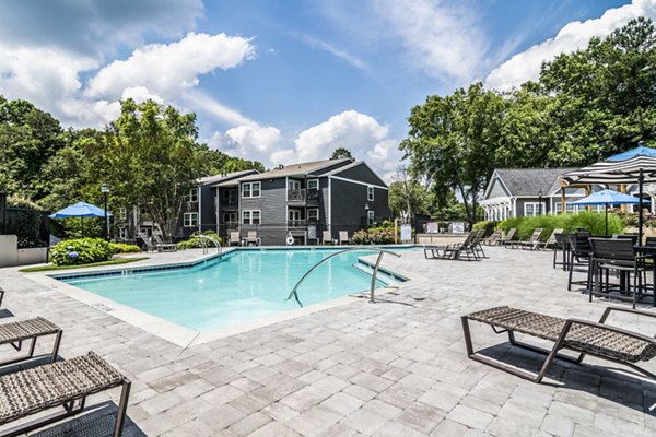 Sparkling blue pool surrounded by lush greenery at Avana Woods Apartments offering luxury living and leisure
