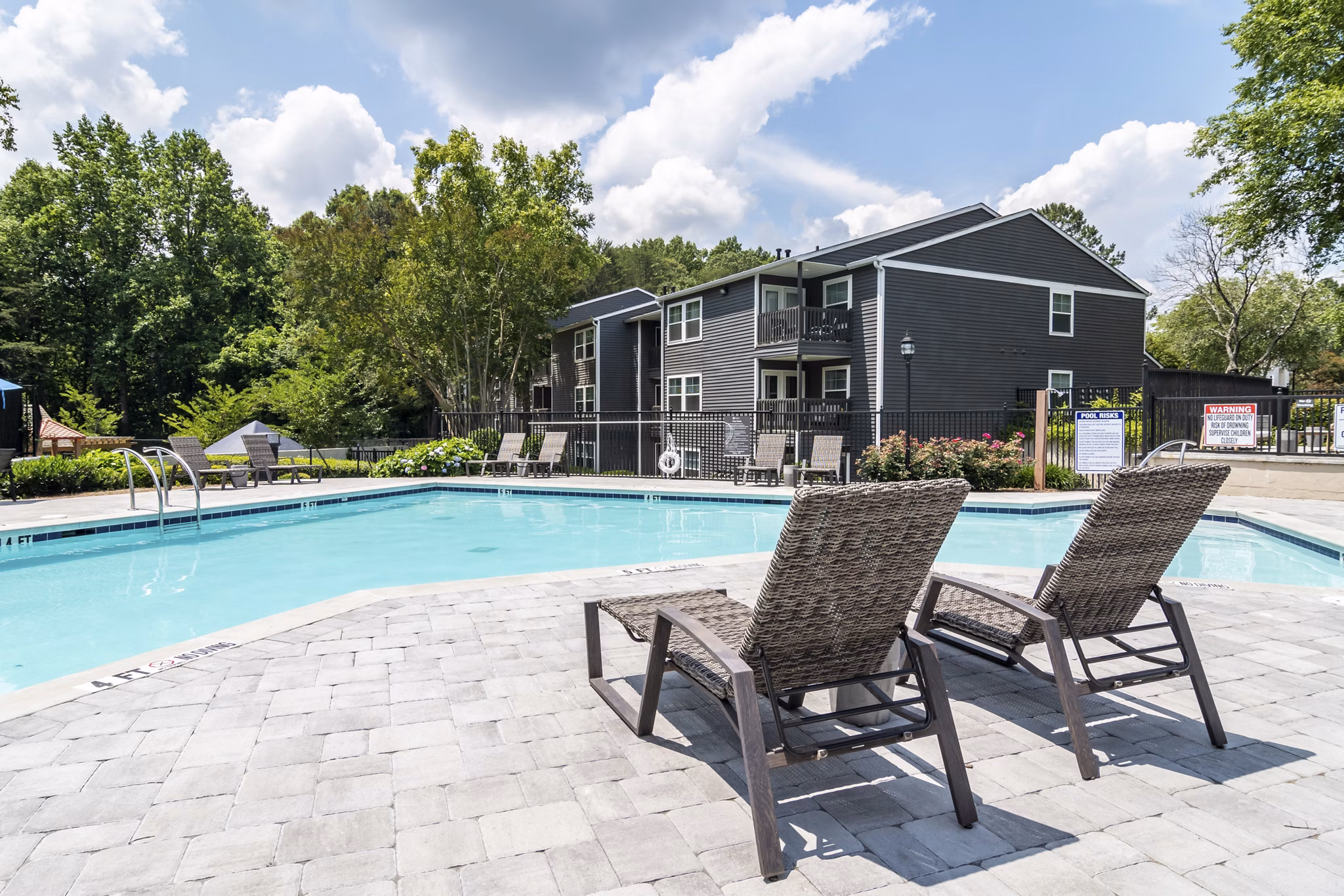 Relaxing pool area at Avana Woods Apartments with surrounding greenery, perfect for sunny days and leisure activities