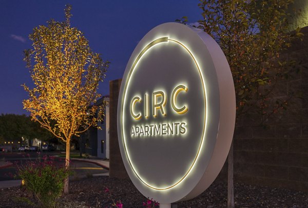 CIRC Apartments illuminated sign surrounded by trees and plants in a vibrant outdoor setting