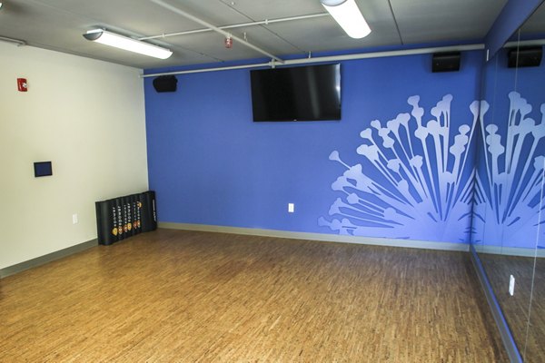 Yoga studio with mirrored walls and wooden floors at The Paxon Apartments, offering a relaxed environment for fitness enthusiasts