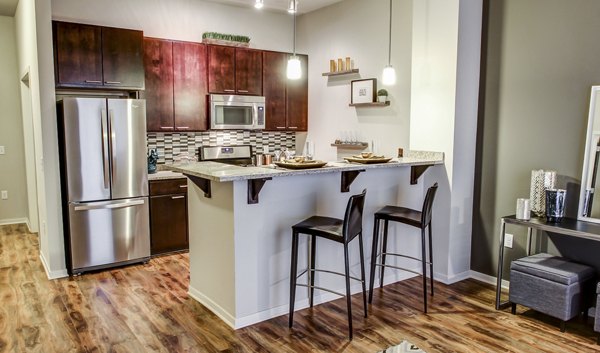 Modern kitchen featuring stainless steel appliances and granite countertops at The Paxon Apartments