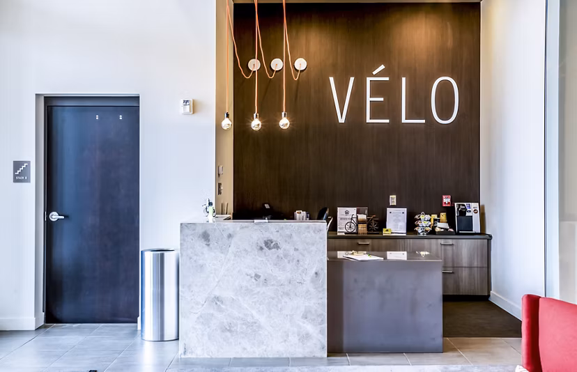 Front desk lobby with modern design at Velo Apartments, featuring a spacious layout and stylish decor in a vibrant community setting