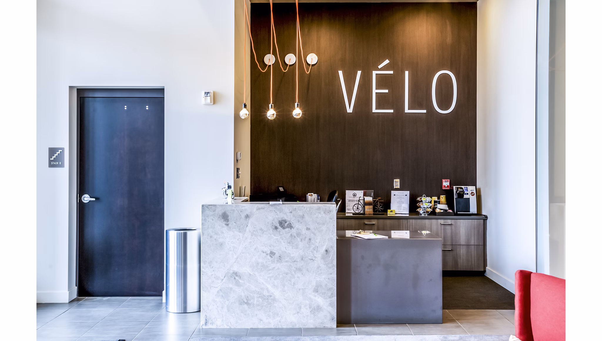 Front desk lobby with modern design at Velo Apartments, featuring a spacious layout and stylish decor in a vibrant community setting