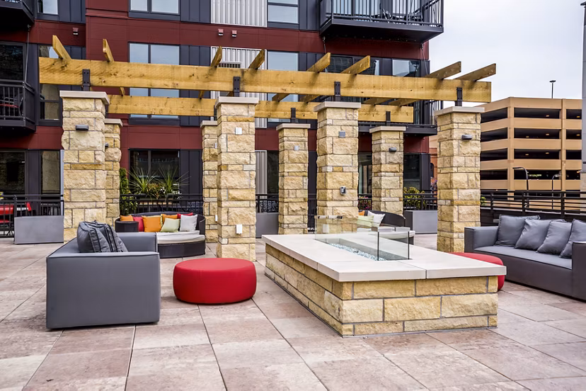 Fire pit surrounded by modern seating at Velo Apartments patio offering luxury outdoor living spaces