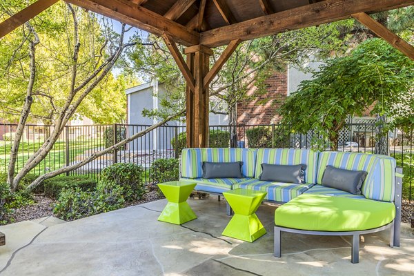 Outdoor pool patio with modern seating and lush greenery at Spring Park Apartments