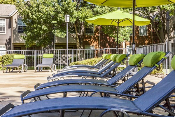 Contemporary pool lounge seating area at Spring Park Apartments with umbrellas and sunbeds for relaxation