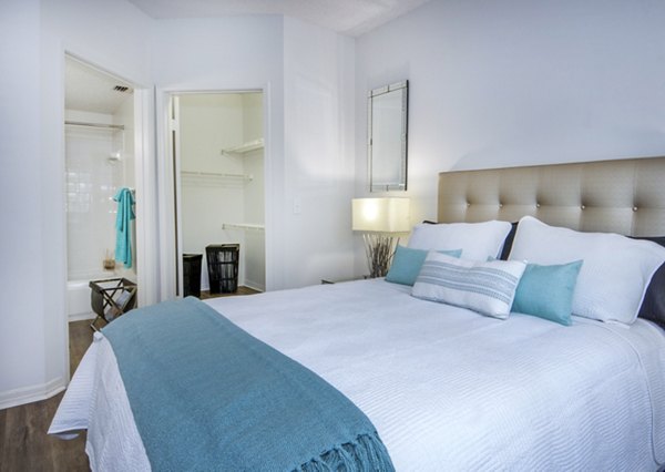 Bedroom with modern furnishings and large windows at Mira Flores Apartments