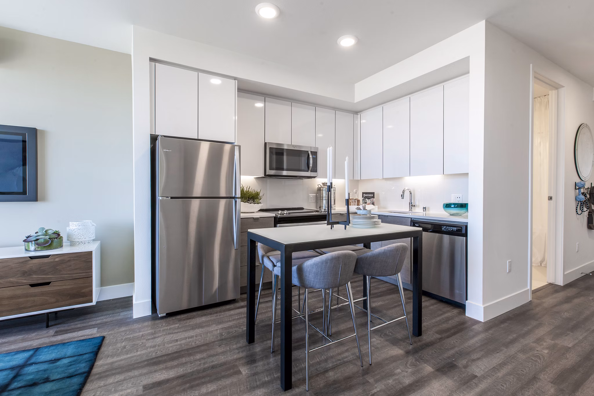 Modern kitchen with dark cabinets, stainless steel appliances, a small dining table with two chairs, and place settings