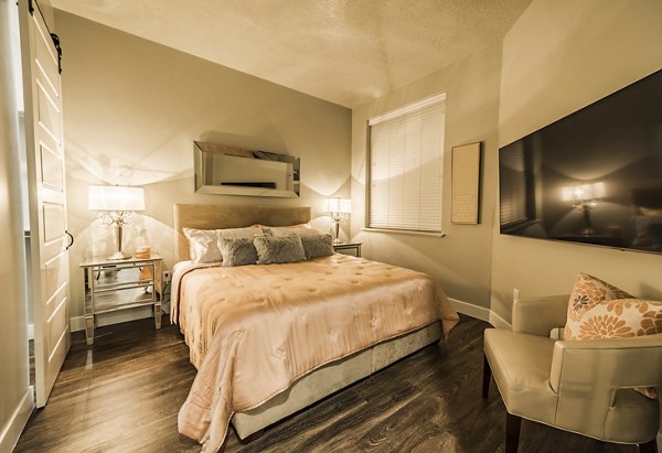 Bedroom with modern furnishings and large windows at Hardware Village Apartments
