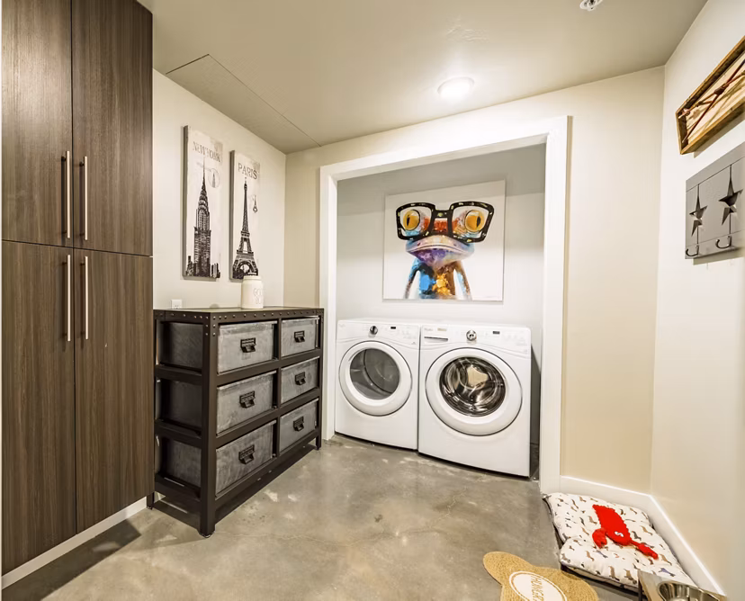 Laundry room with modern appliances and ample storage at Hardware Village Apartments, offering convenience and efficiency for residents