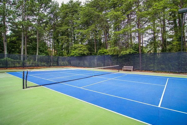 Tennis court with bright green surface at The Prato at Midtown Apartments, offering a premium sports experience in a luxury setting