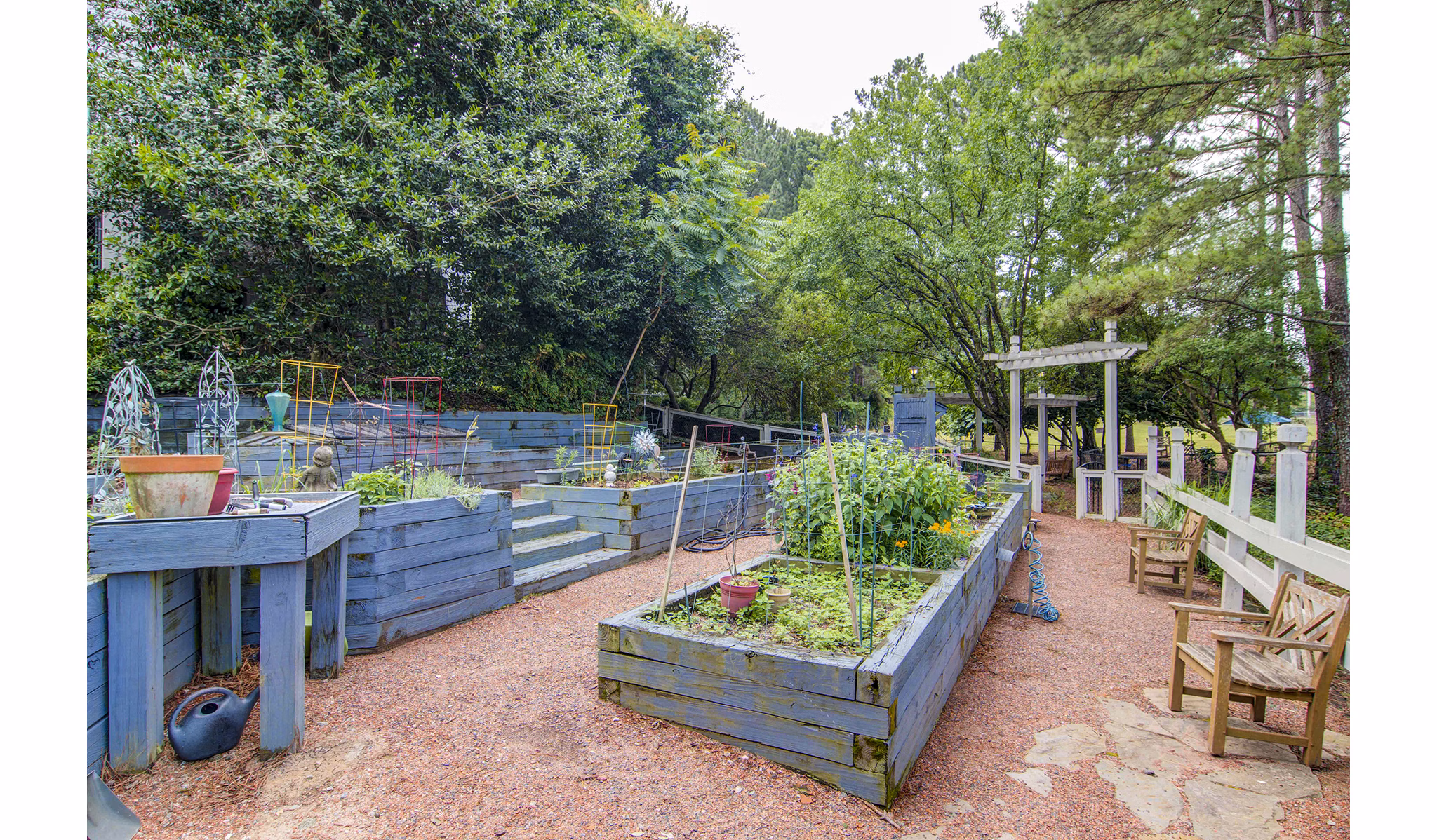 Community garden at The Prato at Midtown Apartments with lush greenery and vibrant flower beds offering a peaceful retreat for residents