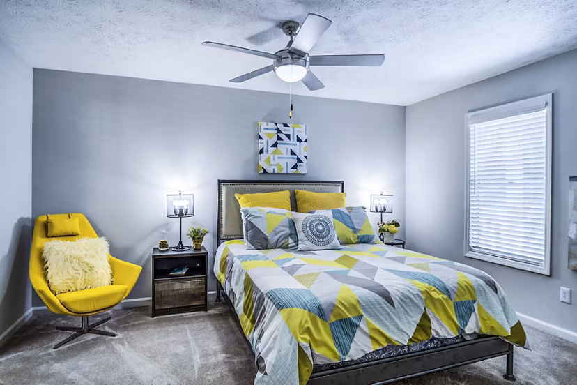Cozy bedroom with modern decor in Junction at Vinings Apartments featuring natural light and plush bedding