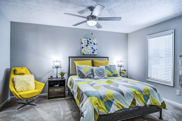 Cozy bedroom with modern decor in Junction at Vinings Apartments featuring natural light and plush bedding