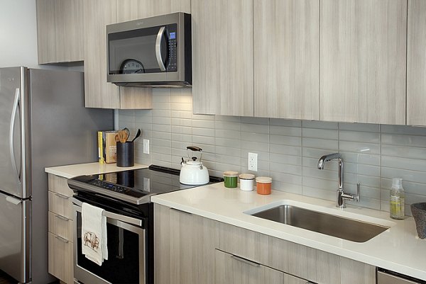 Contemporary kitchen with stainless steel appliances at SOVA Apartments, featuring sleek countertops and modern cabinetry