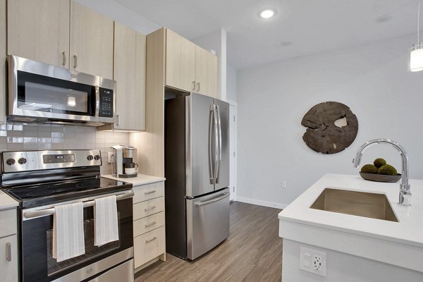Modern kitchen with granite countertops and stainless steel appliances at Overture 9th + CO Apartments