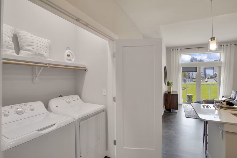 Laundry room with modern appliances at Overture 9th + CO Apartments, a luxury living community by Greystar