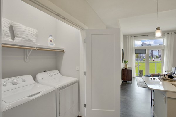 Laundry room with modern appliances at Overture 9th + CO Apartments, a luxury living community by Greystar