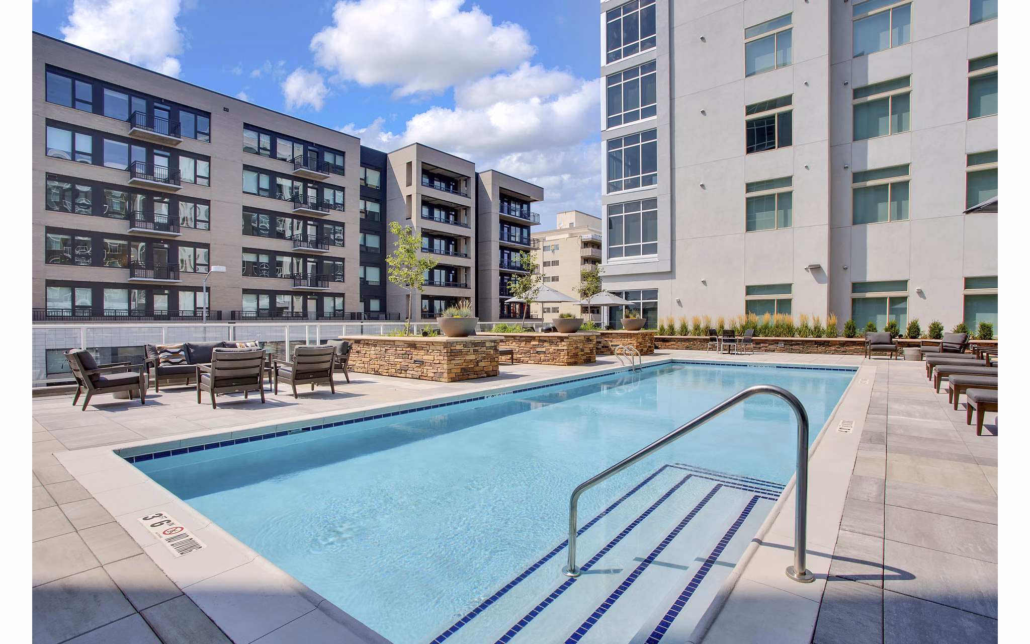 Stylish pool area with sun loungers and lush landscaping at Overture 9th + CO Apartments