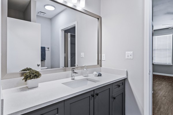 Bathroom with sleek fixtures and marble countertops at Avana on Main Apartments