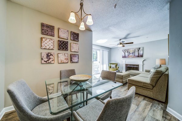 Dining room with modern chandelier and wooden dining table at Autumn Woods Apartments