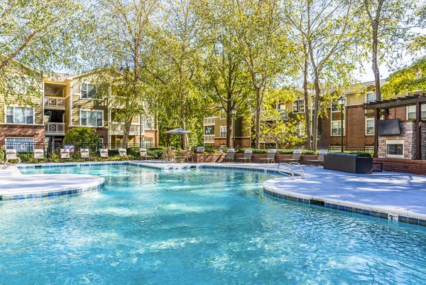 Resort-style pool at Autumn Woods Apartments with lounge chairs and landscaped greenery