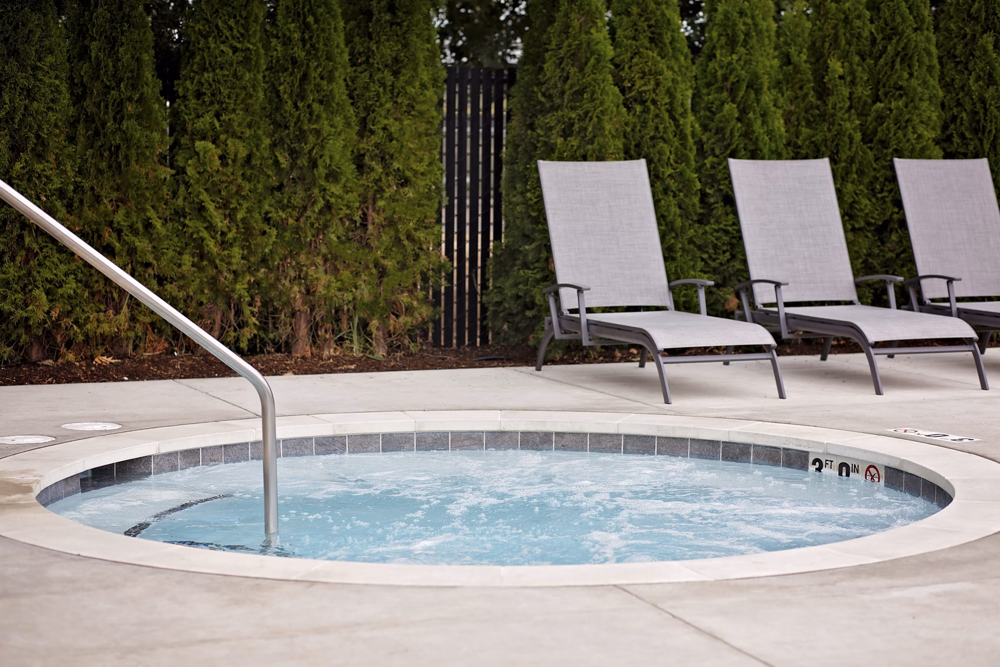 Relaxing outdoor hot tub at Trio Pointe luxury apartments with natural landscaping and seating area
