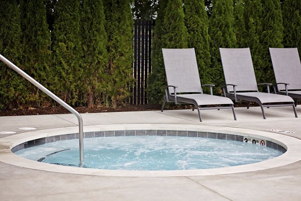 Relaxing outdoor hot tub at Trio Pointe luxury apartments with natural landscaping and seating area