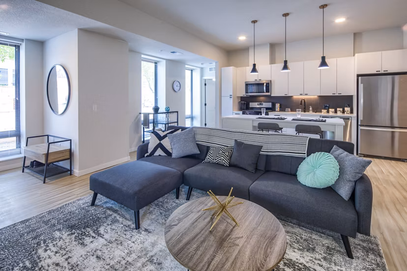 Modern living room with cozy seating and large windows at Irvine Exchange Apartments